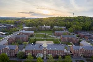 "Brick campus buildings with a sunset and forest in back."
